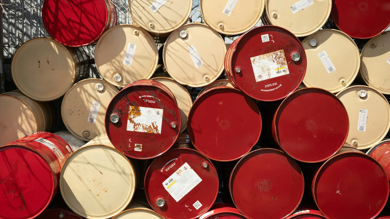 Stacked red and beige 55-gallon steel drums in storage